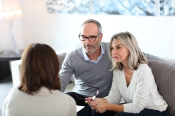 A Person talking to a couple in a living room